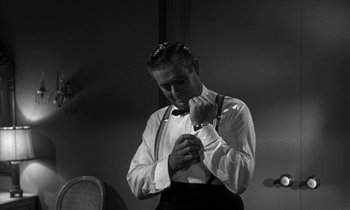 Movie still from “The Facts of Life” (1960), directed by Melvin Frank – A black and white photo of a man adjusting his bow tie; Medium shot, Low angle