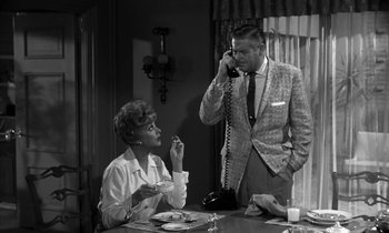 Movie still from “The Facts of Life” (1960), directed by Melvin Frank – An older man talking on a phone while a woman sits at a table; Medium shot, High angle