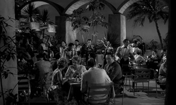 Movie still from “The Facts of Life” (1960), directed by Melvin Frank – A black and white photo of people sitting at tables; Wide shot, High angle