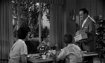 Movie still from “The Facts of Life” (1960), directed by Melvin Frank – A group of people sitting around a table; Medium shot, Over the shoulder angle