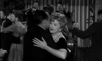 Movie still from “The Facts of Life” (1960), directed by Melvin Frank – An older woman and a younger man dance in front of an orchestra; Medium shot, Over the shoulder angle