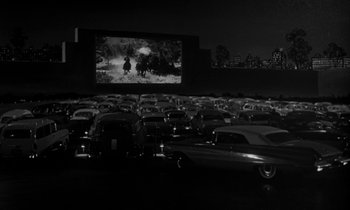 Movie still from “The Facts of Life” (1960), directed by Melvin Frank – An outdoor drive - in movie screen with a lot of cars parked in front of it; Extreme Wide shot, High angle