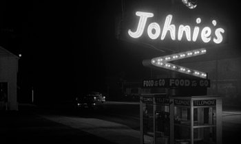 Movie still from “The Facts of Life” (1960), directed by Melvin Frank – A black - and - white photo of a neon sign at night; Wide shot, Low angle