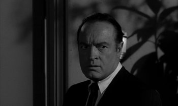 Movie still from “The Facts of Life” (1960), directed by Melvin Frank – A man wearing a suit and tie in front of a window; Close Up shot, Low angle