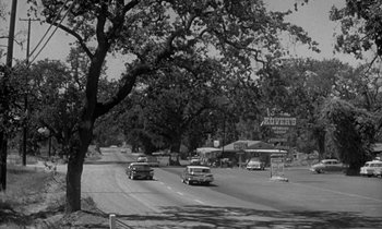 Movie still from “The Facts of Life” (1960), directed by Melvin Frank – A black and white photo of cars driving down a street; Extreme Wide shot, High angle