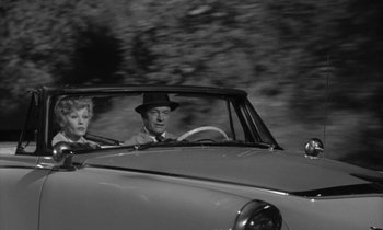 Movie still from “The Facts of Life” (1960), directed by Melvin Frank – A man and a woman driving a car in the road; Wide shot, Low angle