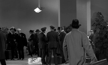Movie still from “The Facts of Life” (1960), directed by Melvin Frank – A black and white photo of a group of men in suits and hats; Wide shot, Low angle