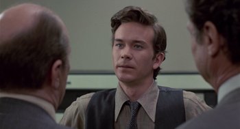 Movie still from “The Falcon and the Snowman” (1985), directed by John Schlesinger – A man wearing a vest and a tie looking into the camera; Close Up shot, Over the shoulder angle