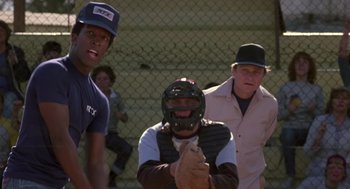 Movie still from “The Falcon and the Snowman” (1985), directed by John Schlesinger – A group of men standing next to each other on top of a baseball field; Medium shot, Over the shoulder angle