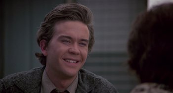 Movie still from “The Falcon and the Snowman” (1985), directed by John Schlesinger – A young man smiling while wearing a suit and tie; Close Up shot, Over the shoulder angle