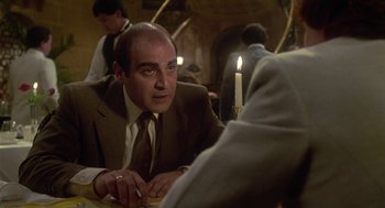 Movie still from “The Falcon and the Snowman” (1985), directed by John Schlesinger – A man sitting at a table with a candle in front of him; Close Up shot, Over the shoulder angle