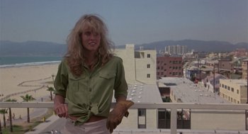 Movie still from “The Falcon and the Snowman” (1985), directed by John Schlesinger – A woman standing on a balcony holding a glove; Medium shot, Low angle