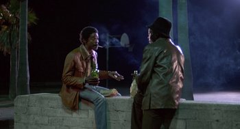 Movie still from “The Falcon and the Snowman” (1985), directed by John Schlesinger – Two men are sitting on a wall and smoking; Medium shot, Low angle