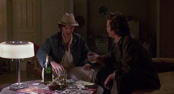 Movie still from “The Falcon and the Snowman” (1985), directed by John Schlesinger – Two men sitting at a table with a glass of wine; Medium shot, Over the shoulder angle