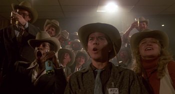 Movie still from “The Falcon and the Snowman” (1985), directed by John Schlesinger – A group of people wearing cowboy hats in a room; Medium shot, Low angle