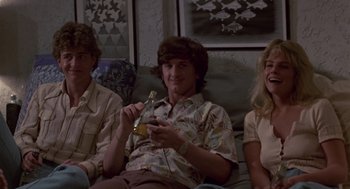 Movie still from “The Falcon and the Snowman” (1985), directed by John Schlesinger – A man sitting next to two other people holding a phone; Medium shot, Low angle