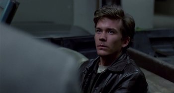 Movie still from “The Falcon and the Snowman” (1985), directed by John Schlesinger – A man in a leather jacket sitting on a train; Close Up shot, Over the shoulder angle