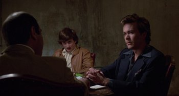 Movie still from “The Falcon and the Snowman” (1985), directed by John Schlesinger – A group of people sitting at a table; Medium shot, Over the shoulder angle