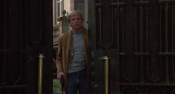 Movie still from “The Falcon and the Snowman” (1985), directed by John Schlesinger – A man standing in front of an old building; Medium shot, Low angle