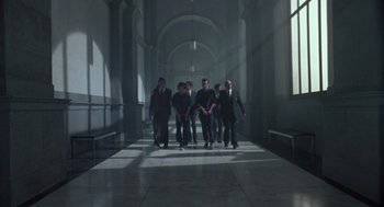 Movie still from “The Falcon and the Snowman” (1985), directed by John Schlesinger – A group of people walking down a hall way; Wide shot, Low angle
