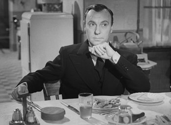 Movie still from “The Fallen Idol” (1948), directed by Carol Reed – A black and white photo of a man sitting at a dinner table; Medium shot, Over the shoulder angle