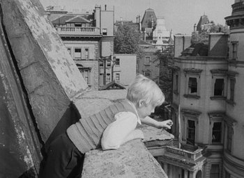 Movie still from “The Fallen Idol” (1948), directed by Carol Reed – A little boy that is sitting on a ledge; Wide shot, High angle