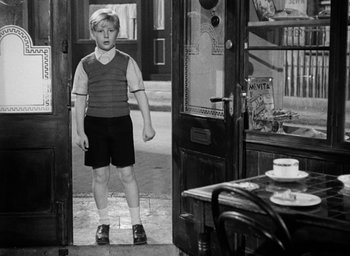 Movie still from “The Fallen Idol” (1948), directed by Carol Reed – A young boy standing in a doorway of a restaurant; Wide shot, High angle