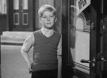 Movie still from “The Fallen Idol” (1948), directed by Carol Reed – A young boy standing in front of an open door; Medium shot, High angle