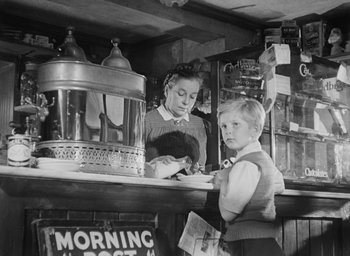 Movie still from “The Fallen Idol” (1948), directed by Carol Reed – A woman and a boy are standing at a counter; Medium shot, Low angle