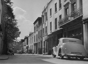 Movie still from “The Fallen Idol” (1948), directed by Carol Reed – An old car is parked on the side of the street; Extreme Wide shot, Low angle