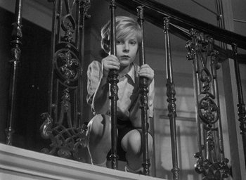 Movie still from “The Fallen Idol” (1948), directed by Carol Reed – A young girl is sitting on the stairs holding a phone; Medium shot, Low angle