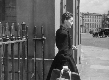 Movie still from “The Fallen Idol” (1948), directed by Carol Reed – A woman walking down the street holding a purse; Medium shot, Over the shoulder angle