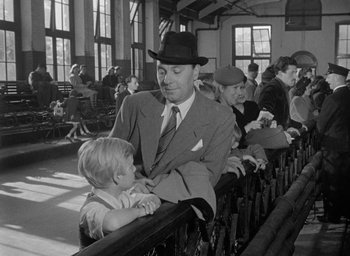 Movie still from “The Fallen Idol” (1948), directed by Carol Reed – An old photo of a man and a child in a train station; Medium shot, Over the shoulder angle