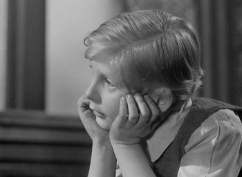 Movie still from “The Fallen Idol” (1948), directed by Carol Reed – A little girl sitting in front of a wall with her head resting on her hand; Close Up shot, High angle