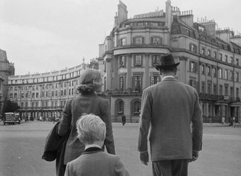 Movie still from “The Fallen Idol” (1948), directed by Carol Reed – A black and white photo of a man , woman , and child walking in front of a building; Wide shot, Low angle