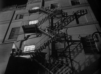 Movie still from “The Fallen Idol” (1948), directed by Carol Reed – A black and white photo of a fire escape on the side of a building; Extreme Wide shot, Low angle