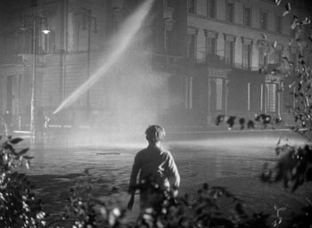 Movie still from “The Fallen Idol” (1948), directed by Carol Reed – A man standing in a street near a fire hydrant at night; Wide shot, Low angle