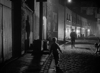 Movie still from “The Fallen Idol” (1948), directed by Carol Reed – A young boy walking down a street at night; Extreme Wide shot, High angle