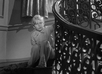 Movie still from “The Fallen Idol” (1948), directed by Carol Reed – A little boy sitting on the stairs of a house; Medium shot, High angle