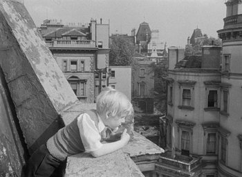 Movie still from “The Fallen Idol” (1948), directed by Carol Reed – A little boy laying on the ledge of an old building; Medium shot, High angle