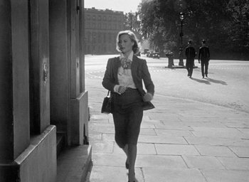 Movie still from “The Fallen Idol” (1948), directed by Carol Reed – A black and white photo of a woman walking down the street; Medium shot, Low angle