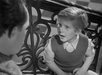 Movie still from “The Fallen Idol” (1948), directed by Carol Reed – A young boy sitting next to a woman on a bench; Medium shot, Over the shoulder angle