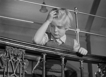 Movie still from “The Fallen Idol” (1948), directed by Carol Reed – A young boy leaning on a railing with his hand on his head; Close Up shot, High angle