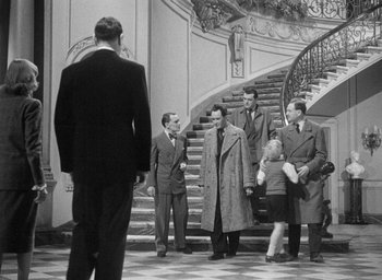 Movie still from “The Fallen Idol” (1948), directed by Carol Reed – A black and white photo of a group of men in suits; Wide shot, Over the shoulder angle
