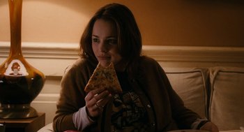 Movie still from “The Family Stone” (2005), directed by Thomas Bezucha – A woman sitting at a table eating a piece of pizza; Medium shot, Over the shoulder angle