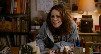 Movie still from “The Family Stone” (2005), directed by Thomas Bezucha – A woman sitting at a table in front of books; Medium shot, High angle