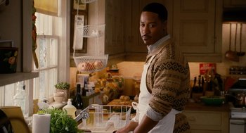 Movie still from “The Family Stone” (2005), directed by Thomas Bezucha – A man standing in a kitchen preparing a meal; Medium shot, Over the shoulder angle