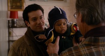 Movie still from “The Family Stone” (2005), directed by Thomas Bezucha – A man holding a baby wearing a hat; Close Up shot, Over the shoulder angle