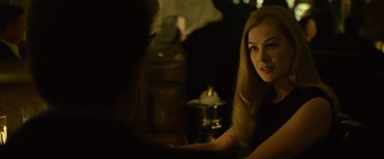 Movie still from “Gone Girl” (2014), directed by David Fincher – A woman sitting at a table in a dark room; Close Up shot, Over the shoulder angle