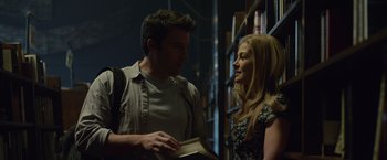 Movie still from “Gone Girl” (2014), directed by David Fincher – A man and a woman standing next to each other in a library; Medium shot, Low angle